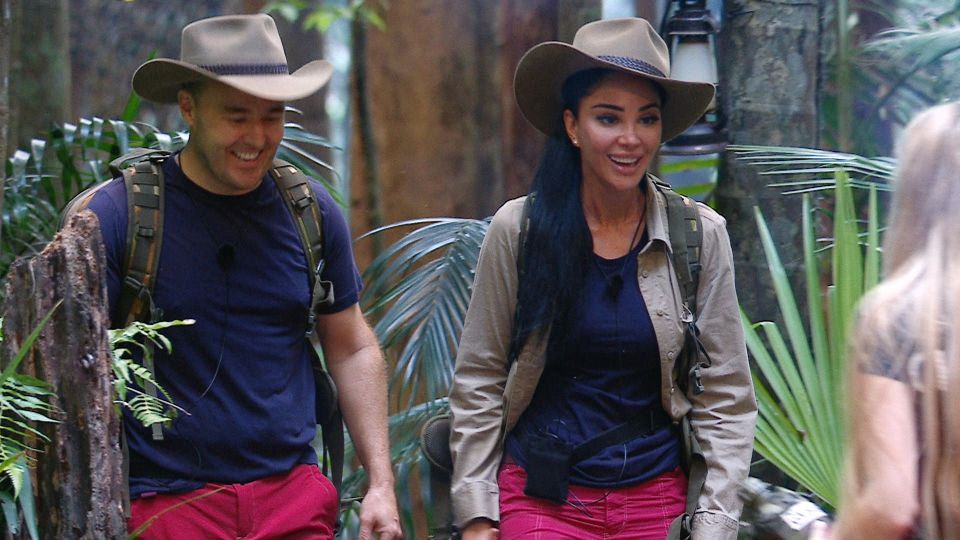 a man and a woman wearing cowboy hats are walking through the jungle
