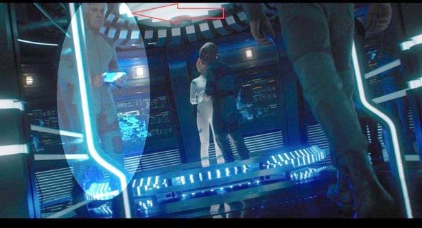 a man and a woman are standing in a futuristic room .