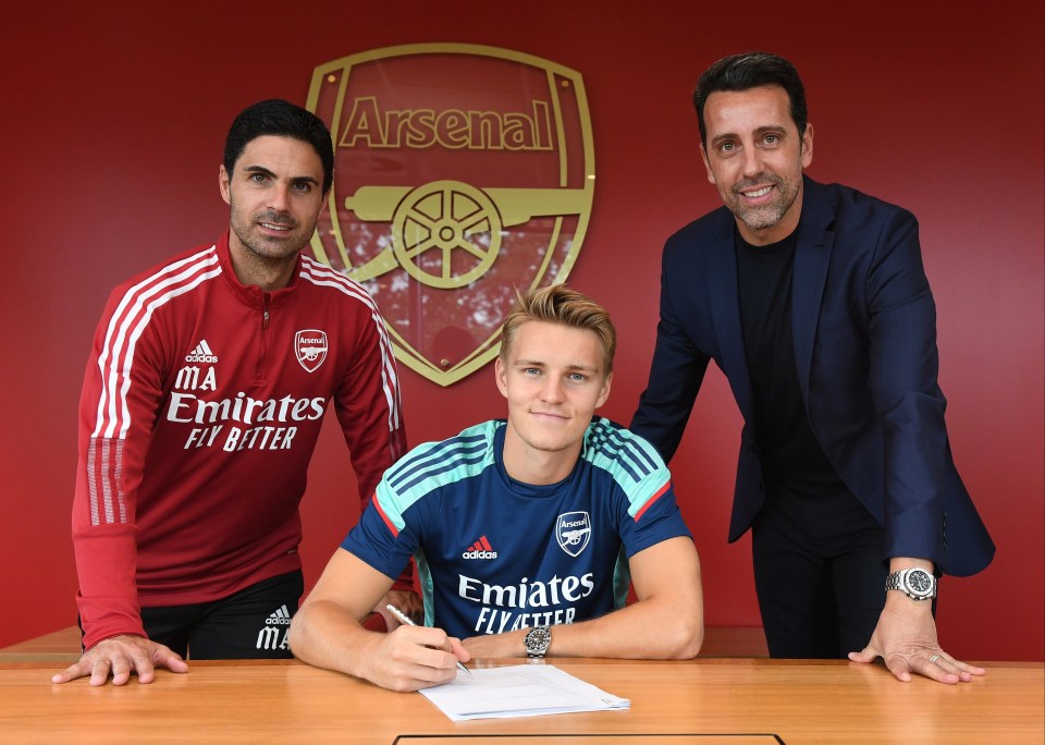 a man in an emirates fly better shirt signs a contract