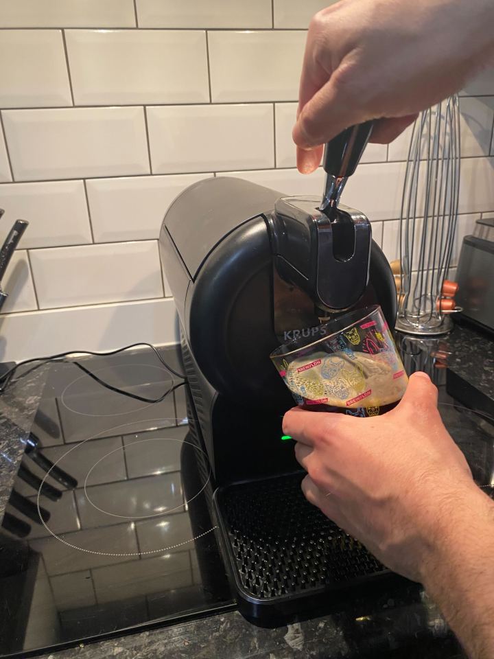 A person pouring beer from a Krups beer dispenser into a glass.