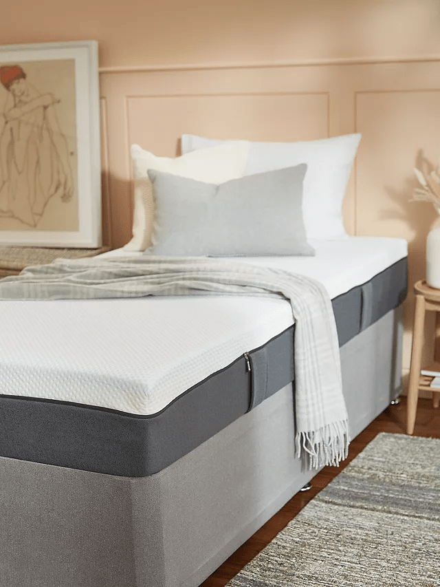 Single bed with grey base and white mattress.