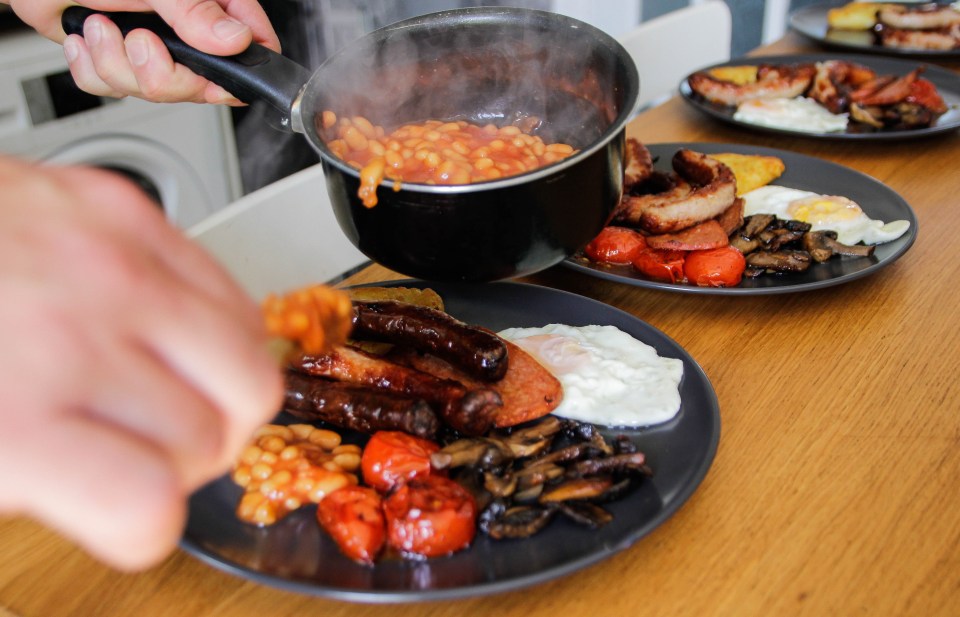Close-up of a person serving a full Irish breakfast.
