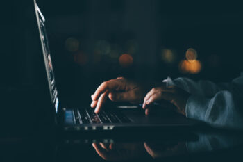 Freelance woman working on laptop at the night. Close up hand with laptop.