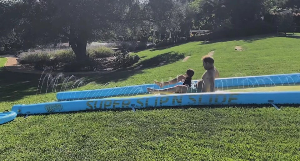 a man and child are playing on a super slipn slide