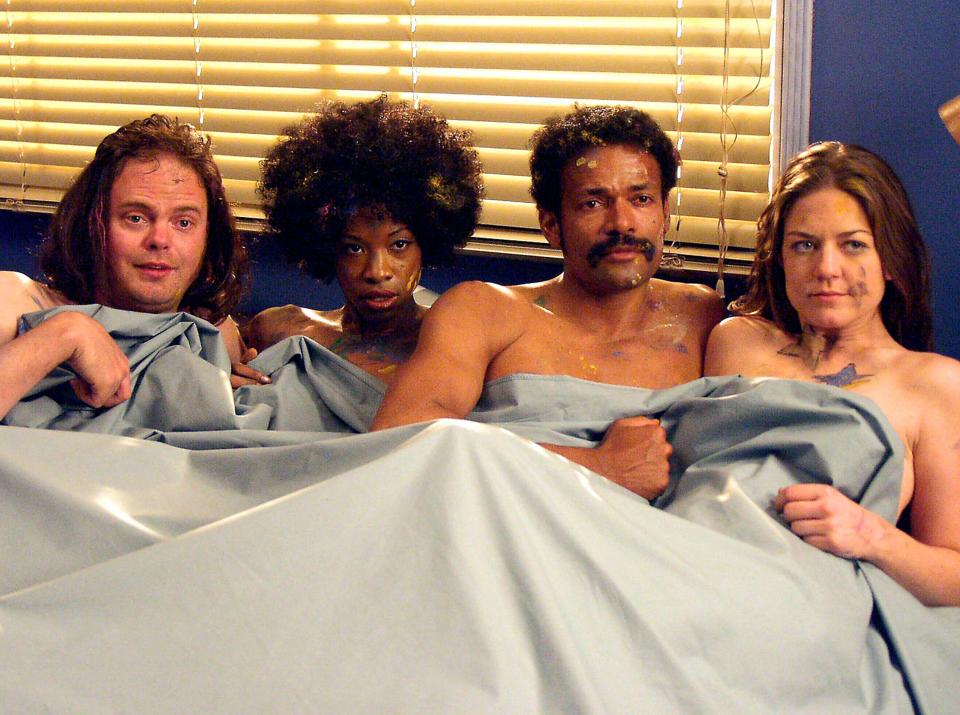 a man and two women are laying on a bed with their faces painted