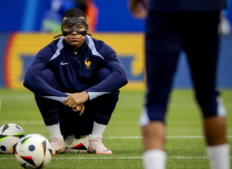 a soccer player wearing a mask sits on the field