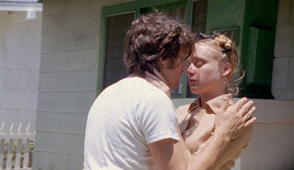 a man and a woman are kissing in front of a house