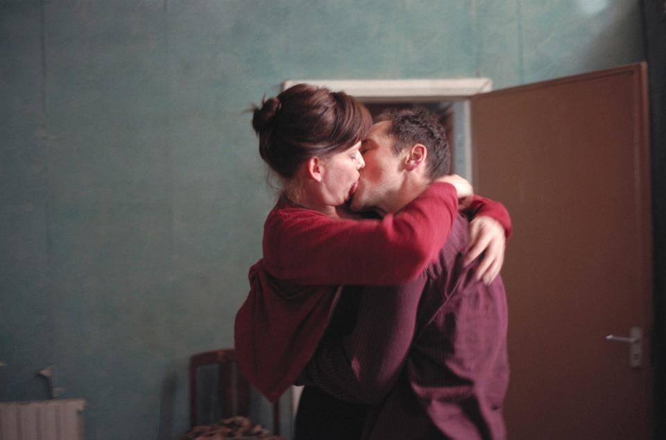 a man and woman kissing in front of a blue wall