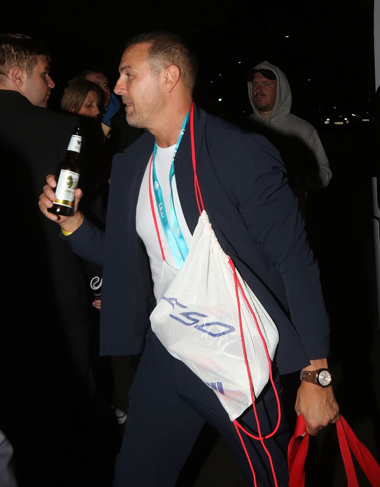 a man in a suit is holding a bottle of beer