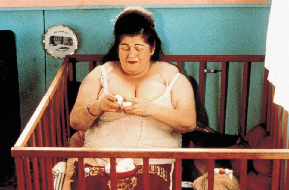 a woman is sitting in a crib with a picture of a camper on the wall behind her