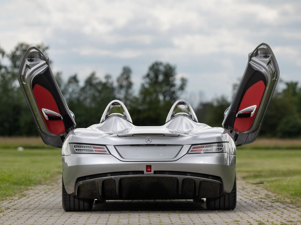 the back of a silver mercedes with its doors open
