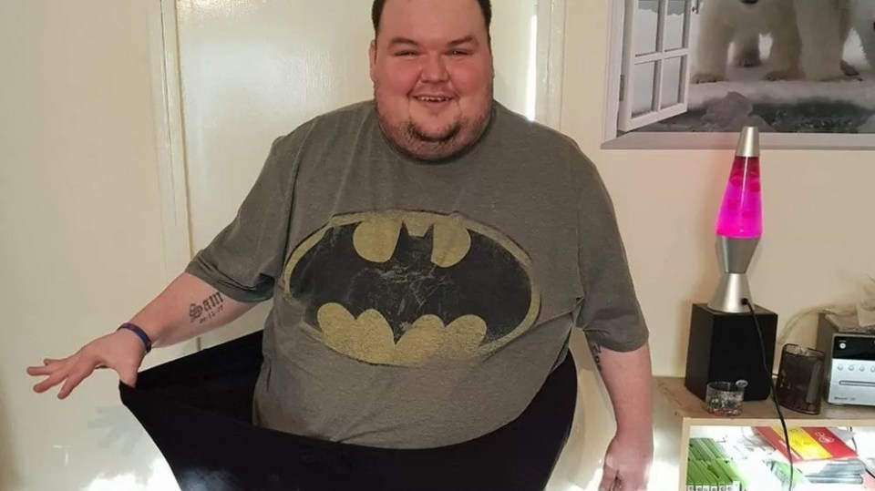 a man wearing a batman t-shirt has a tattoo on his arm that says ' i love you '