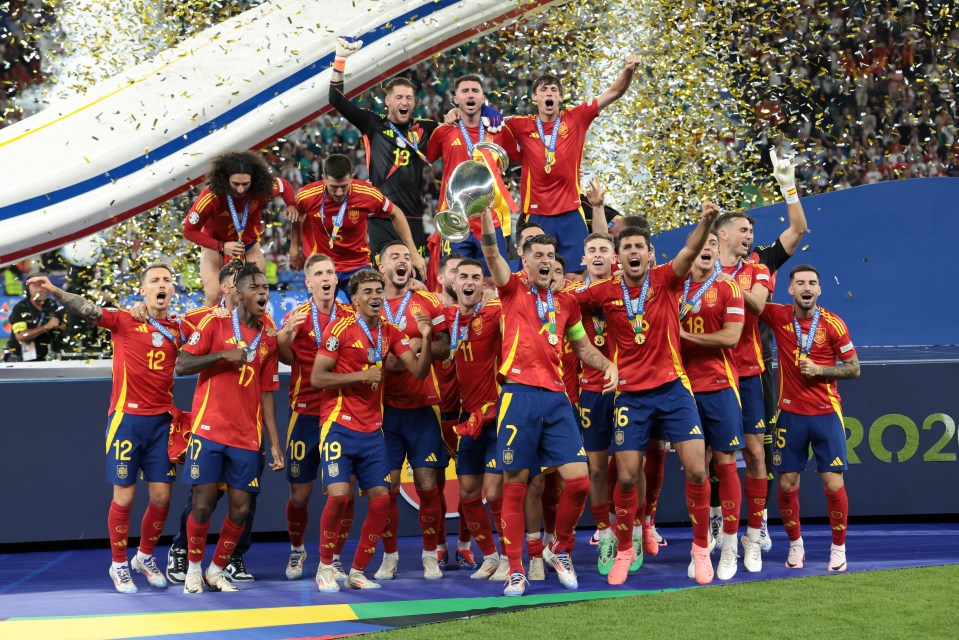 a group of soccer players celebrate with a trophy