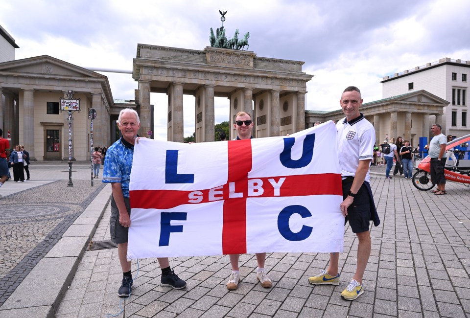 three men holding a flag that says l selby fc