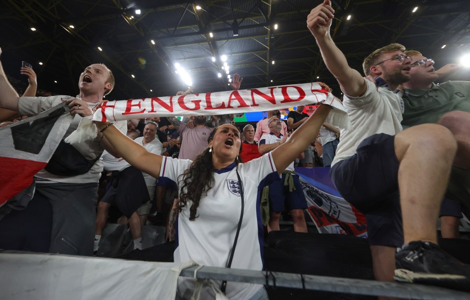 a woman holds up a scarf that says england