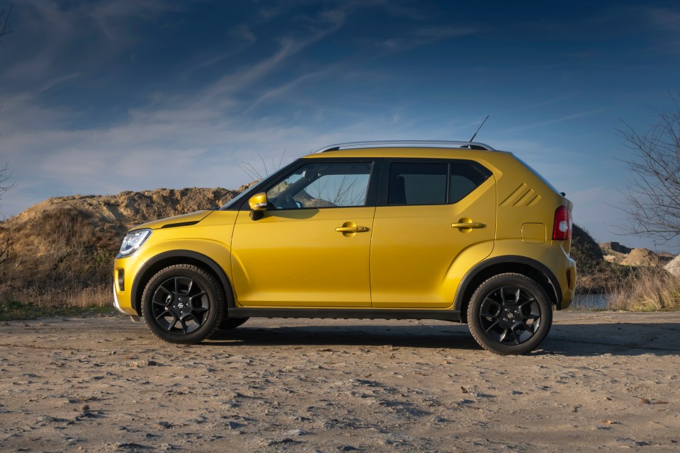 a yellow car is parked on a dirt road