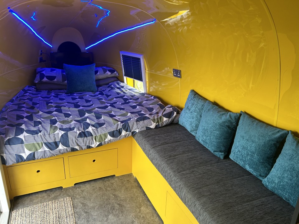 a bed in a yellow room with blue pillows