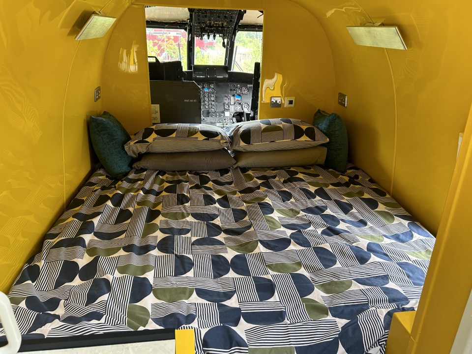 a bed in a yellow room with a patterned blanket