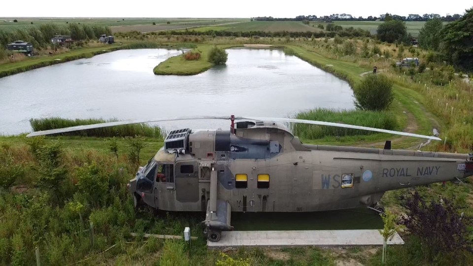 a royal navy helicopter is parked near a lake