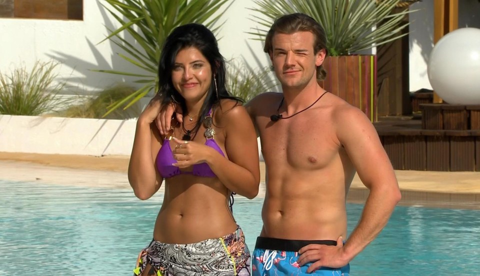 a man and a woman are standing next to a pool and the woman is wearing a bikini