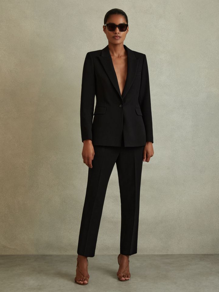 a woman is wearing a black suit and sunglasses