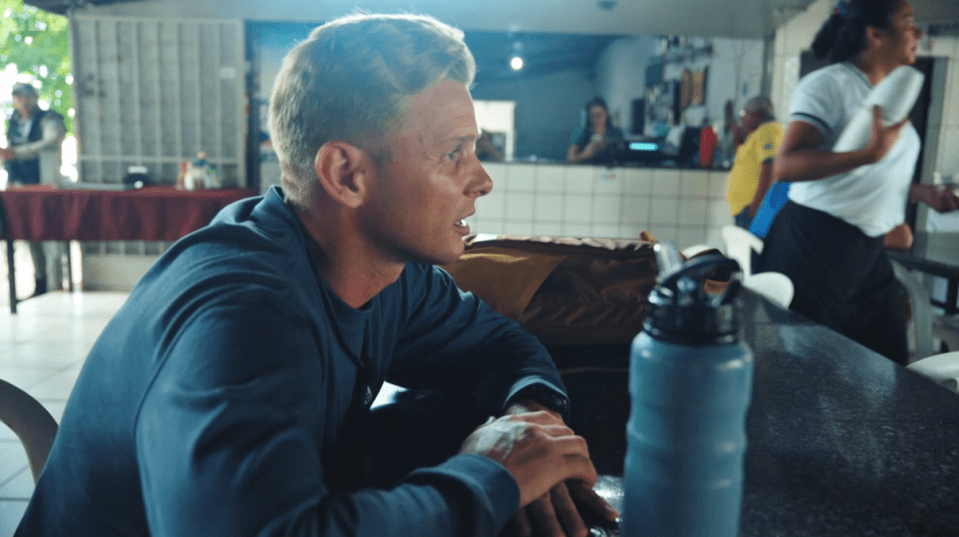 a man sits at a table with a water bottle in front of him