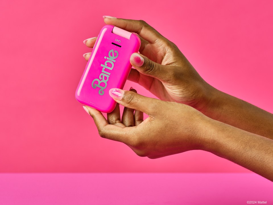 a woman holds a pink barbie phone in her hands