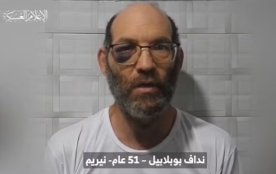 a man wearing glasses and a white shirt with arabic writing on it