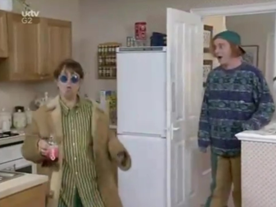 two people in a kitchen with uktv g2 on the screen