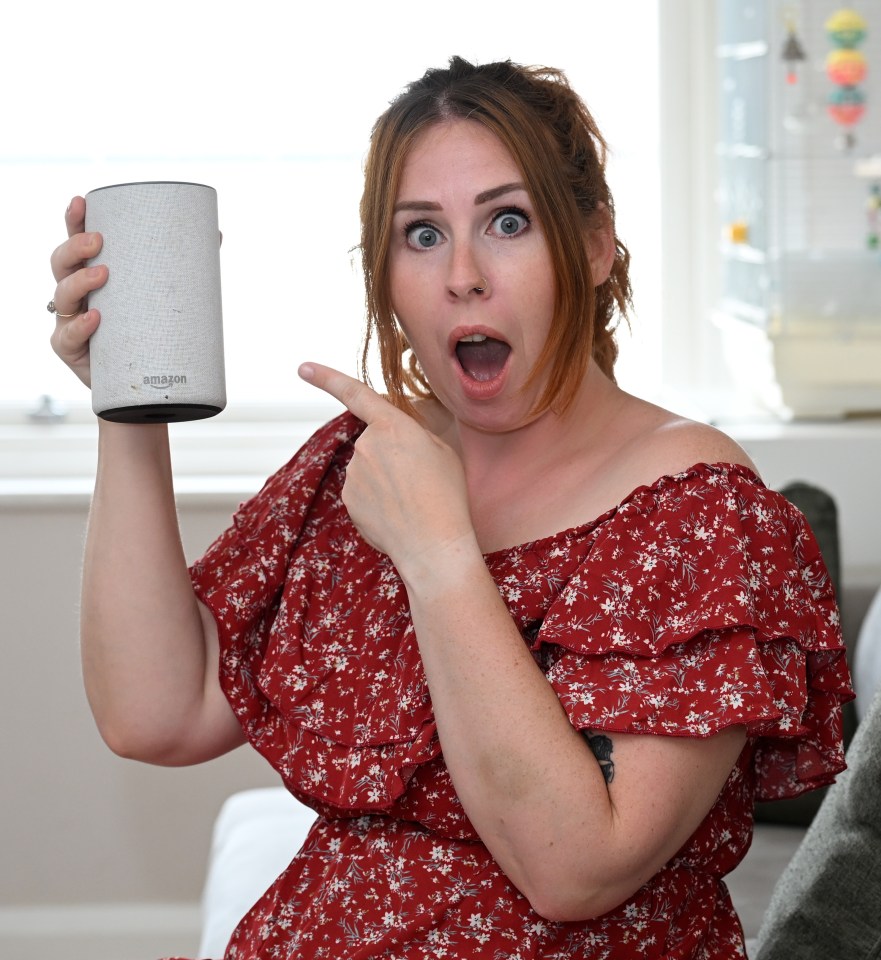 a woman in a red dress is holding an amazon speaker