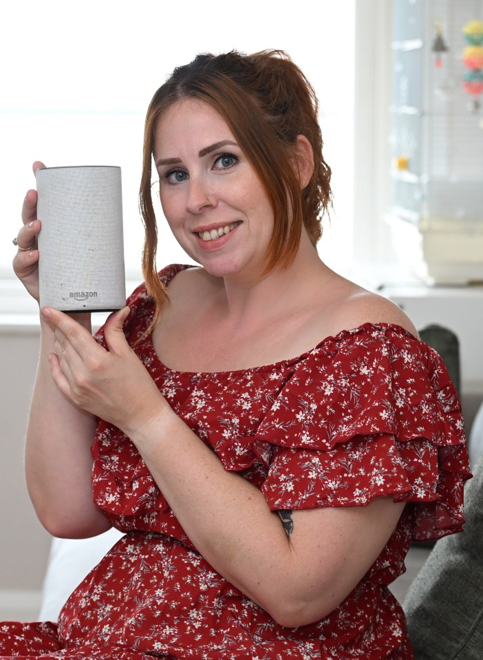 a woman in a red dress is holding an amazon speaker