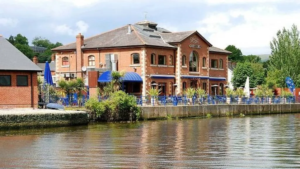 a large brick building is sitting next to a body of water .
