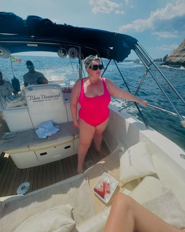 a woman in a pink swimsuit stands on a boat that says blue diamond