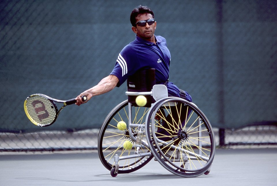 a man in a wheelchair is playing tennis with a wilson racquet