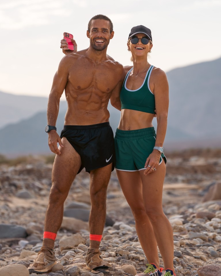a man and a woman are posing for a picture on a rocky beach