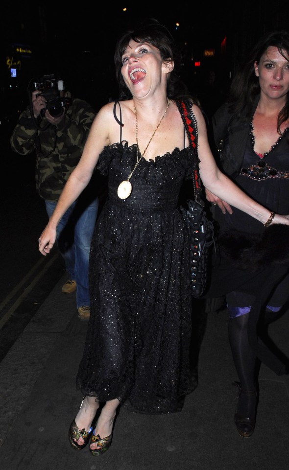 a woman in a black dress is sticking her tongue out