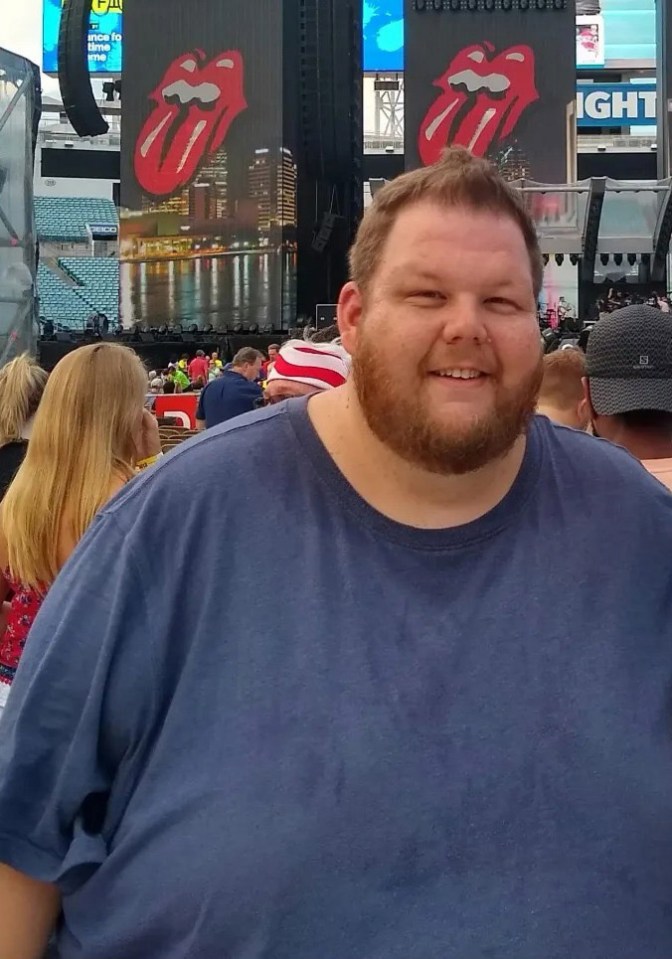 a man stands in front of a rolling stones sign