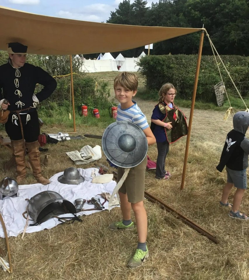 a young boy holding a shield in a field