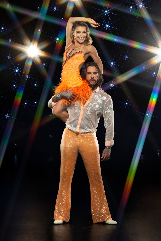 a man is carrying a woman in an orange dress on his shoulders