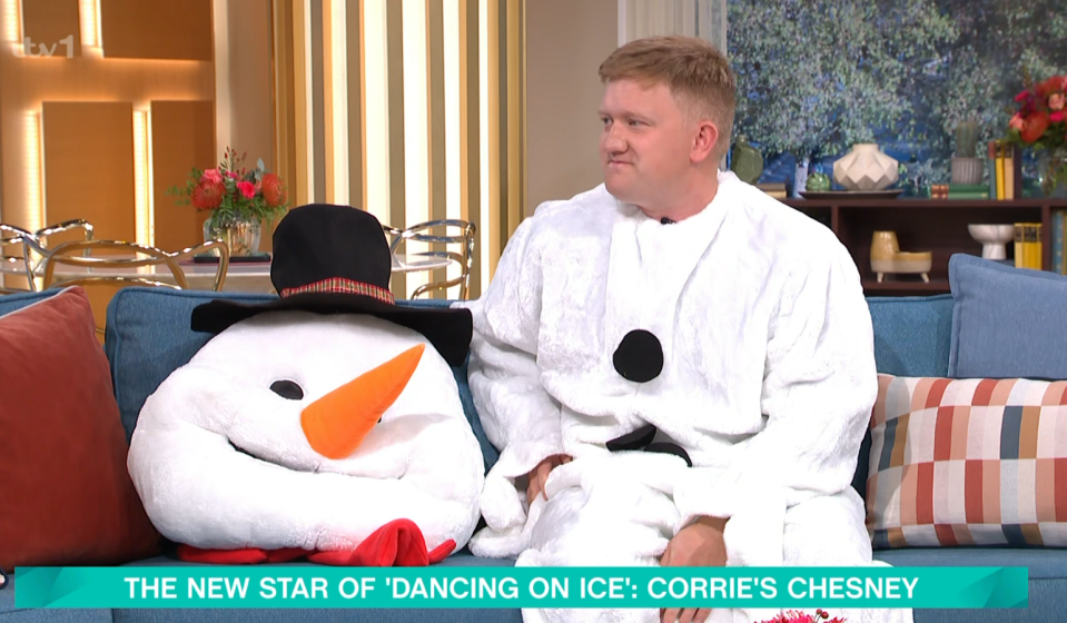 a man is sitting on a couch next to a stuffed snowman