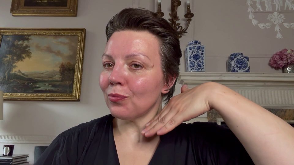 a woman is applying lotion to her neck in front of a painting