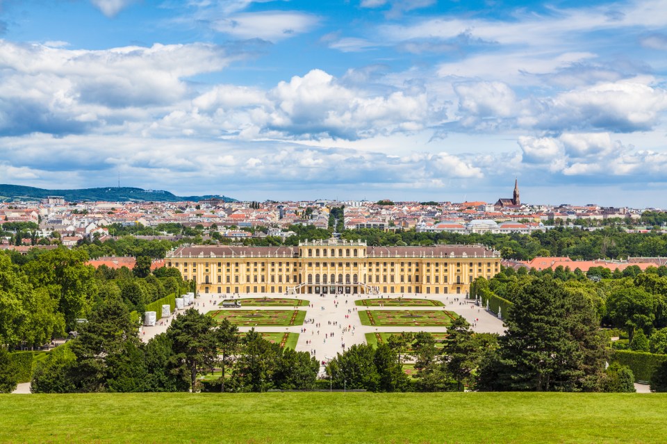 a large building in the middle of a park with a city in the background