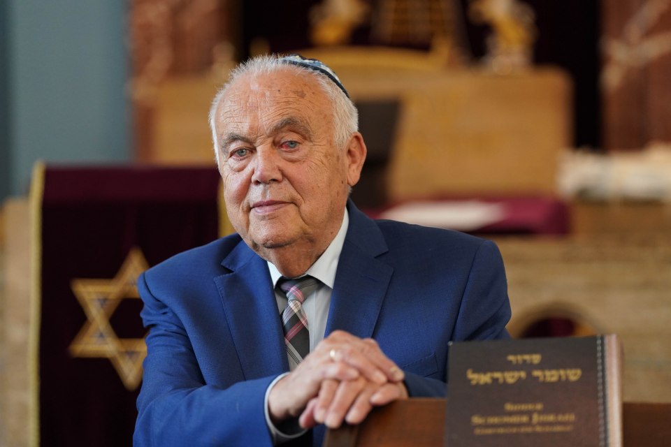 a man in a suit holds a book with hebrew writing on it