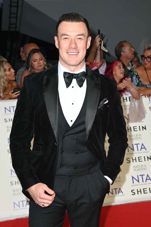 a man in a tuxedo stands on a red carpet that says shein on it