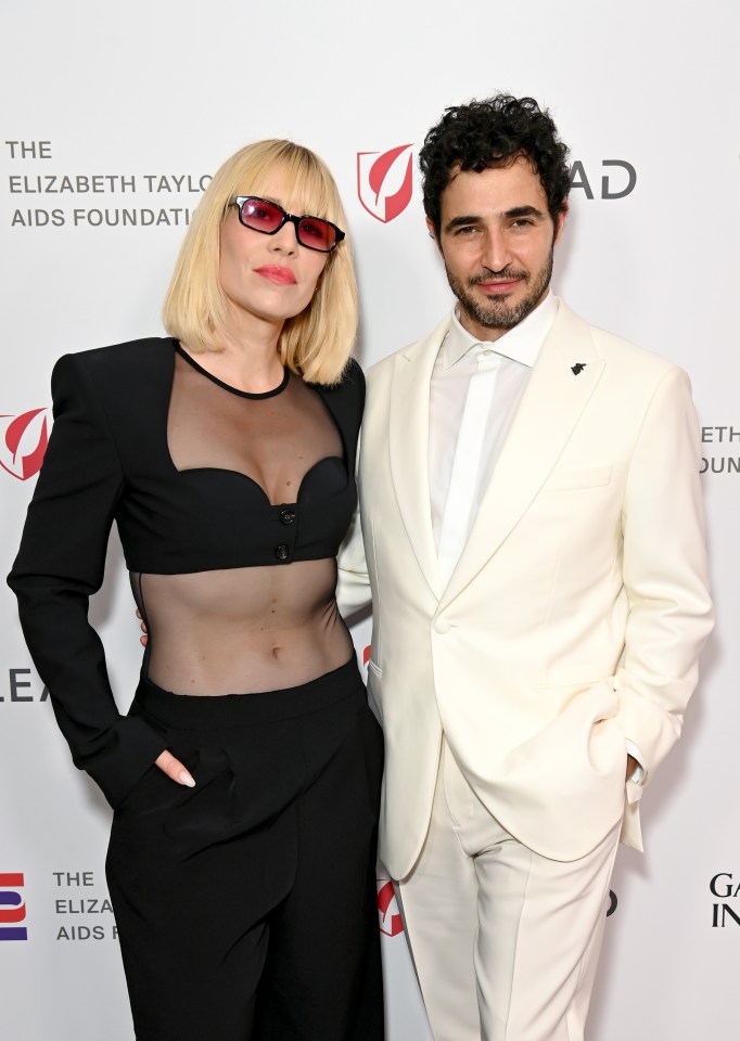 a man and a woman pose for a photo in front of a wall that says the elizabeth taylor aids foundation
