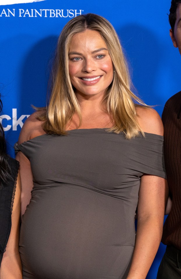 a pregnant woman smiles in front of a blue background that says an paintbrush