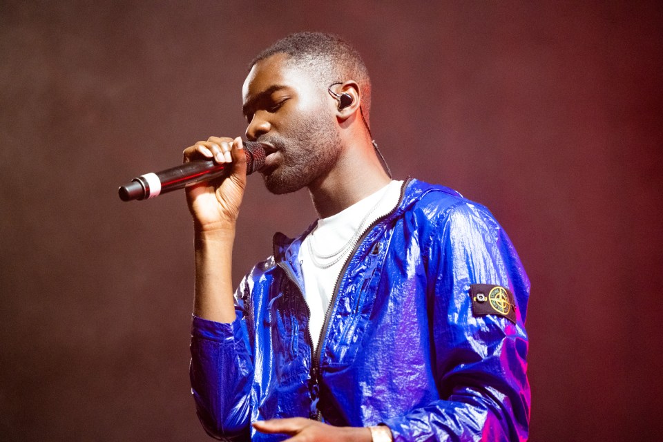 a man in a blue jacket is singing into a microphone