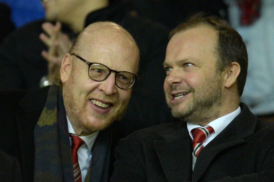a bald man with glasses and a red beard smiles next to another bald man