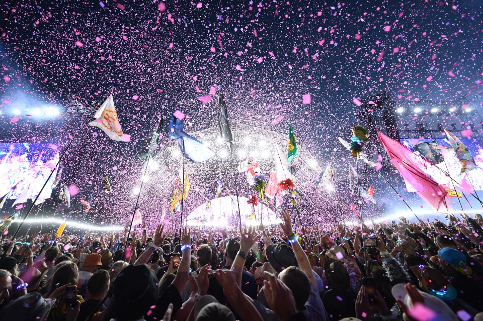 a crowd of people at a concert with confetti falling from the sky