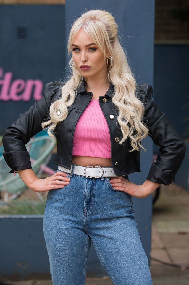 a woman wearing a black leather jacket and a pink crop top